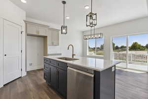 Two tone kitchen with dishwasher, light stone countertops, two tone color scheme, dark wood-style floors, and hanging light fixtures
