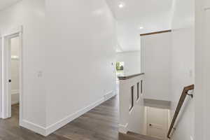 Hallway featuring an upstairs landing, dark wood-style flooring, and recessed lighting