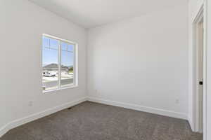 Unfurnished room featuring dark carpet and baseboards