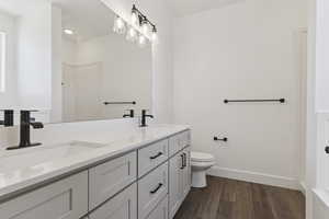 Bathroom with double vanity and dark wood-style flooring