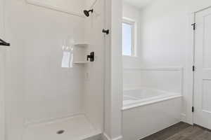 Bathroom with a bath, a shower stall, and dark wood-type flooring