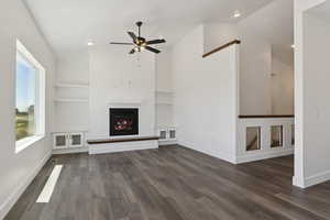 Unfurnished living room featuring lofted ceiling, a fireplace, built in features, ceiling fan, and recessed lighting