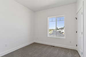 Unfurnished bedroom with dark carpet and a closet