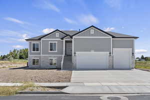 Craftsman inspired home featuring stone siding, an attached garage, concrete driveway, and board and batten siding