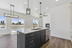 Kitchen with a center island with sink, a fireplace, open floor plan, and decorative light fixtures