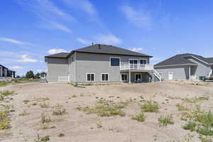 Rear view of property with a deck, stucco siding, and a patio