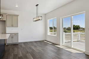 Unfurnished dining area with hanging lights and dark wood-type flooring