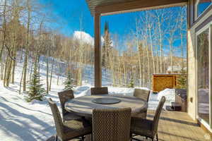 Snow covered patio featuring outdoor dining space and a deck