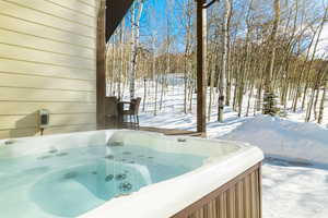 Yard layered in snow with a hot tub
