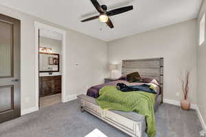 Bedroom with light colored carpet, ensuite bath, and ceiling fan