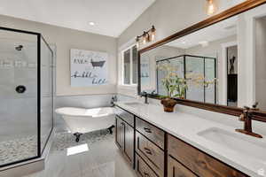 Full bath featuring a shower stall, a wainscoted wall, double vanity, and a freestanding tub