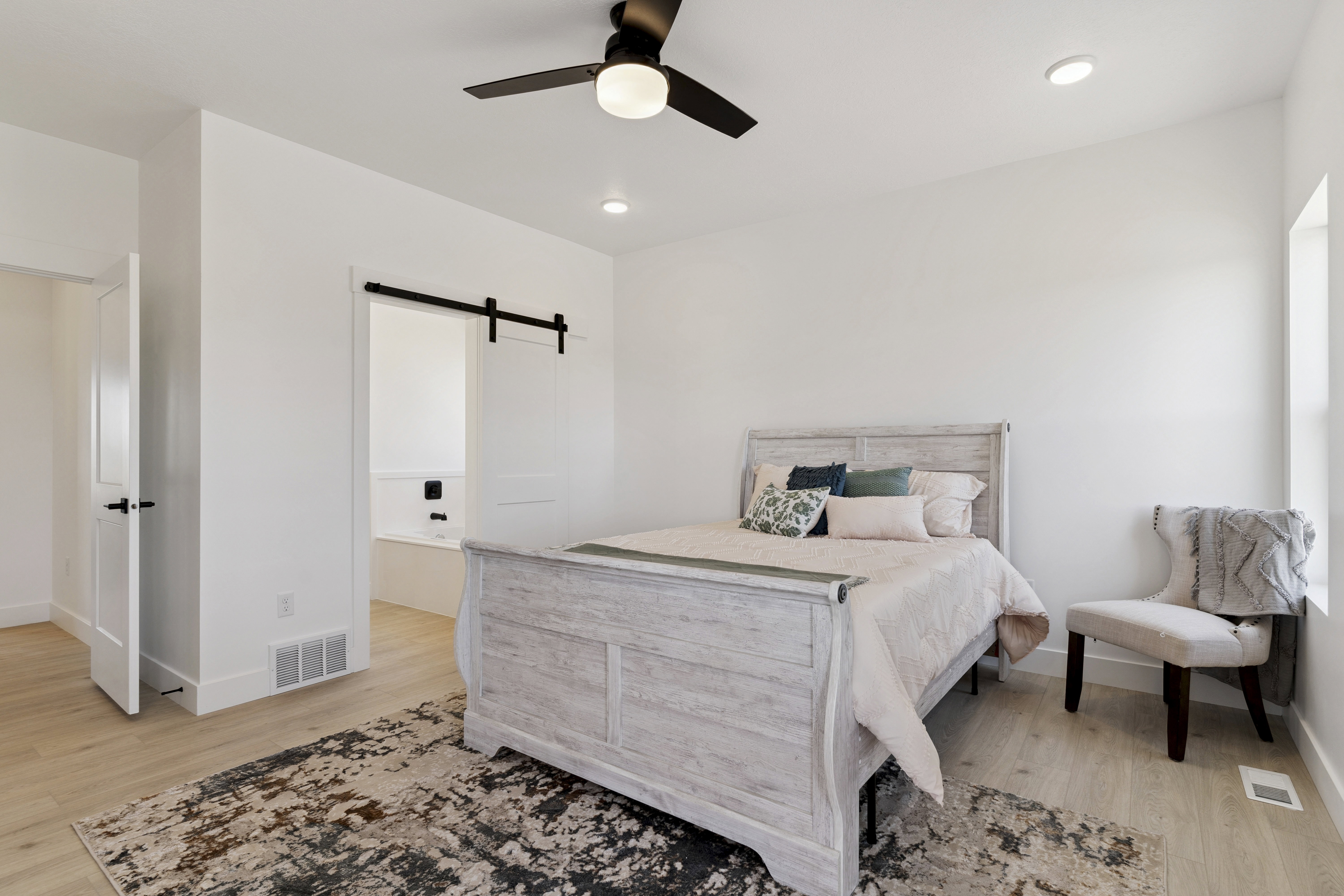 Bedroom with a barn door, light wood-style flooring, ceiling fan, and recessed lighting