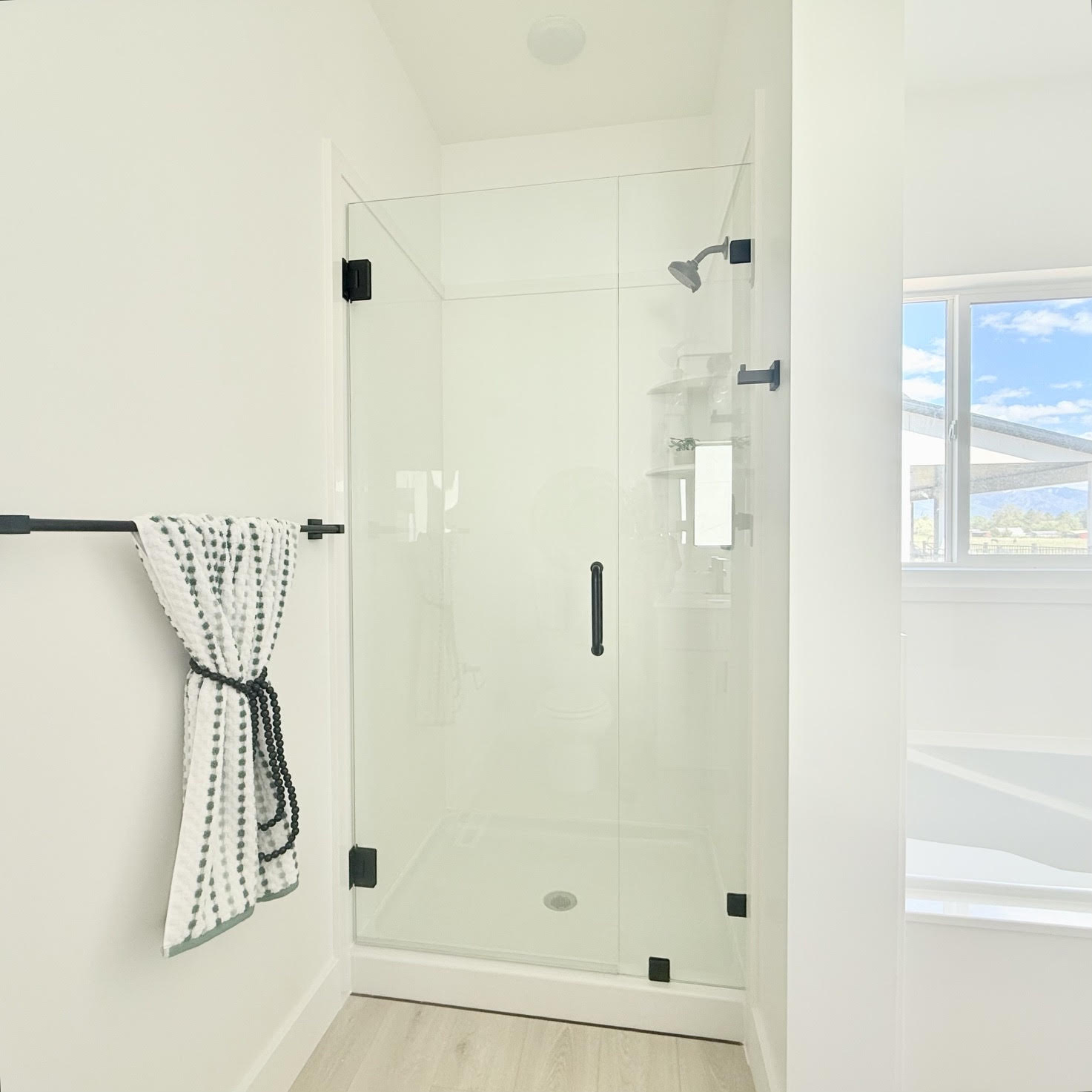Glass-enclosed shower with matte black fixtures and a white shower pan