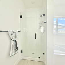 Glass-enclosed shower with matte black fixtures and a white shower pan