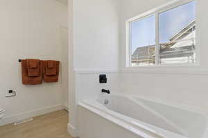 Full bathroom featuring a garden tub and light wood finished floors