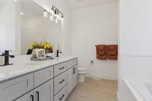 Bathroom featuring double vanity, light wood finished floors, and a bath