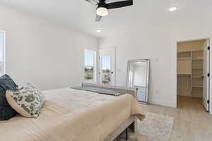 Bedroom featuring a walk in closet, light wood finished floors, a ceiling fan, recessed lighting, and access to outside