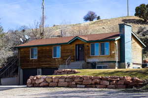 View of front of property featuring a garage, a chimney, and driveway