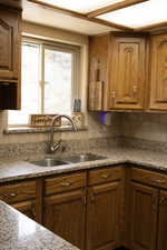 Kitchen featuring wood finish cabinetry, light stone counters, and backsplash