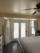 Master bedroom featuring access to exterior, wood-style flooring, a textured ceiling, and a ceiling fan