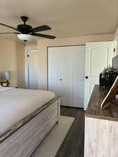 Bedroom with dark wood finished floors, a closet, and ceiling fan