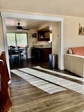 Living area featuring ceiling fan and dark wood-style floors