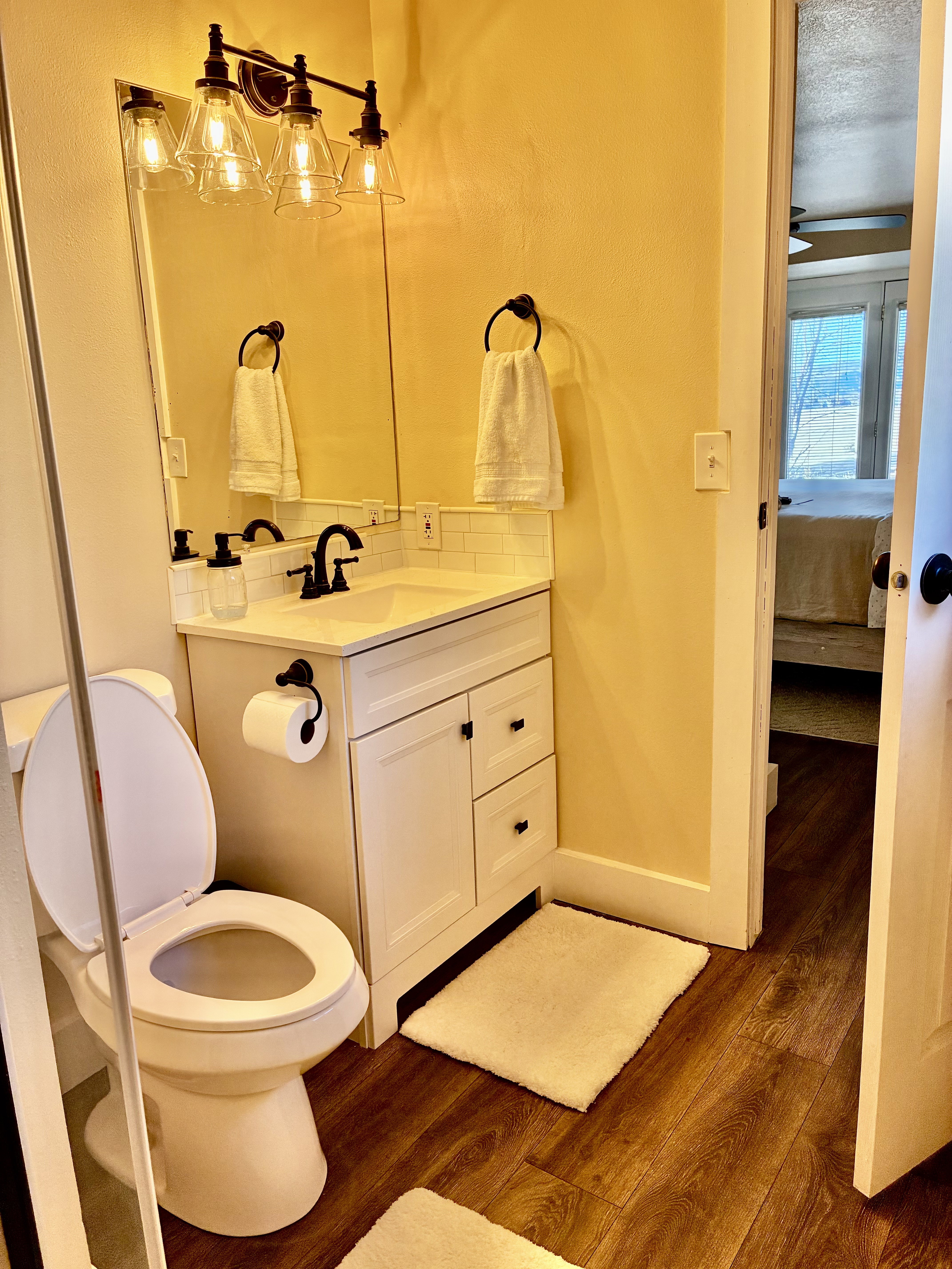 Ensuite bathroom featuring dark wood-style floors, vanity, and decorative backsplash