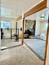 Workout room featuring a textured ceiling, a wood stove, and carpet flooring