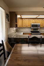Kitchen featuring light stone countertops, stainless steel appliances, decorative backsplash, and a breakfast bar