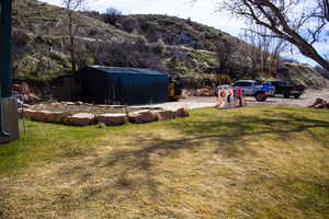 View of grassy yard with a mountain view and an outdoor shed