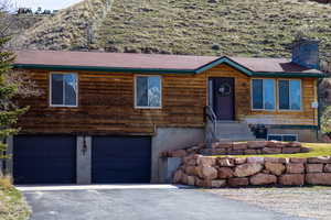 View of front facade featuring a garage, asphalt driveway, and a chimney