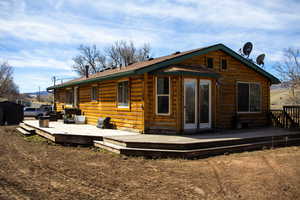Rear view of house featuring a deck and log siding