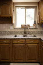 Kitchen featuring wood finish cabinetry, light stone counters, and decorative backsplash