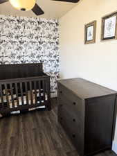 Bedroom featuring wood-style flooring, wallpapered wall, and ceiling fan