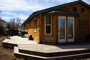 View of side of property with a deck, chicken coop, and log siding