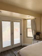 Master bedroom featuring a textured ceiling, access to exterior, and wood finished floors