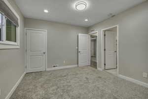 Unfurnished bedroom with light carpet and recessed lighting