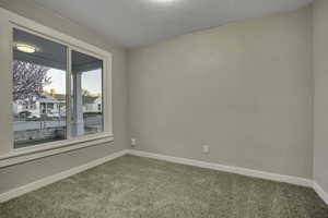 Empty room featuring light carpet and a textured ceiling