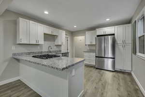 Kitchen featuring stainless steel appliances, light stone counters, white cabinetry, and recessed lighting