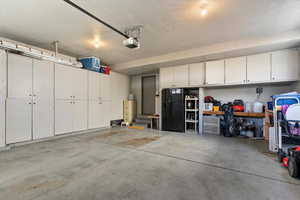Garage with black refrigerator with ice dispenser and a garage door opener