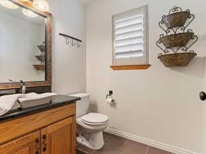Half bathroom featuring dark tile patterned floors and vanity