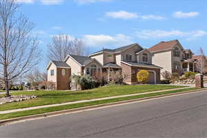 Traditional-style home with a front lawn, an attached garage, brick siding, and driveway