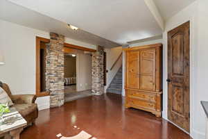 Living area featuring decorative columns, concrete flooring, and a textured ceiling
