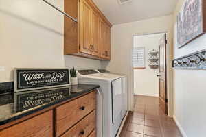 Laundry room with light tile patterned flooring, washer and clothes dryer, and cabinet space