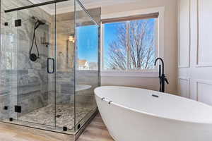 Bathroom featuring light wood-type flooring, a stall shower, a freestanding bath, healthy amount of natural light, and crown molding