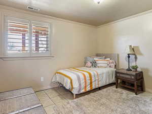 Bedroom with a textured ceiling, crown molding, and light tile patterned flooring