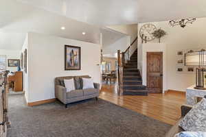 Living area with vaulted ceiling, light colored carpet, light wood-style flooring, and recessed lighting