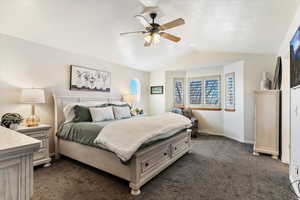 Bedroom featuring dark colored carpet, a ceiling fan, and a textured ceiling