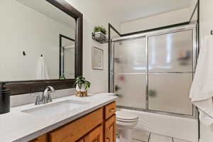 Full bathroom featuring vanity, combined bath / shower with glass door, and light tile patterned flooring