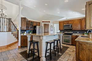Kitchen featuring a kitchen bar, stainless steel appliances, light stone countertops, a kitchen island, and glass insert cabinets